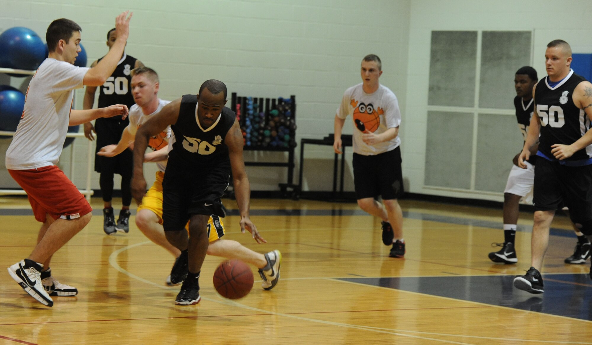WHITEMAN AIR FORCE BASE, Mo. -- A member from the 509th Security Forces-B intramural basketball team, tries to maintain his balance as he dribbles through the 509th Aircraft Maintenance Squadron's defense, Jan. 8. The 509th SFS-B defeated the 509th AMXS 52-42. This victory gives the 509th SFS-B a record of five wins and three losses. (U.S. Air Force photo/Staff Sgt. Nick Wilson) (Released) 
