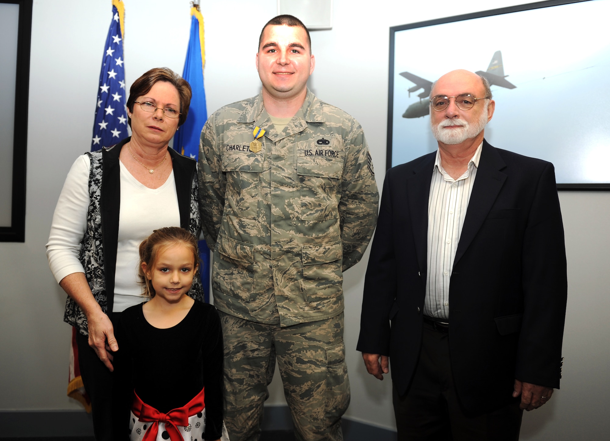 The Wallace family; husband, Michael; wife, Linda; daughter, Brooke, pose for a photo with Staff Sgt. William Charleton, a 19th Component Maintenance Squadron fuel systems craftsman, after Charleton receives the Air Force Commendation Medal for his act of courage and service, Dec. 5, 2012, at Little Rock Air Force Base, Ark. Charleton risked his life to save the Wallace family, including the family pets, from their burning home Aug. 12, 2011.(U.S. Air Force photo by Staff Sgt. Jessica Condit)