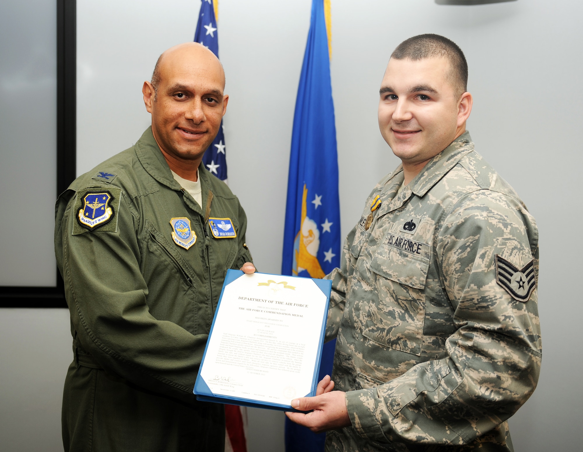 Staff Sgt. William Charleton, a 19th Component Maintenance Squadron fuel systems craftsman, poses with Col. Brian Robinson, 19th Airlift Wing commander, after being awarded the Air Force Commendation Medal for his act of courage and service, Dec. 5, 2012, at Little Rock Air Force Base, Ark. Charleton risked his own life to save a family from their burning home.(U.S. Air Force photo by Staff Sgt. Jessica Condit)