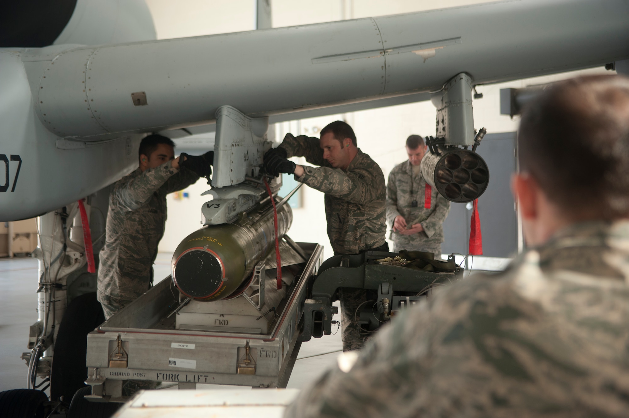 Members of the 74th Aircraft Maintenance Unit work together to use an MHU-83 Jammer to lift a cluster bomb into place on an A-10C Thunderbolt II during an A-10 Weapons Load Crew of the Quarter Competition at Moody Air Force Base, Ga., Jan. 11, 2013. The team raced against the clock to load various munitions onto the aircraft and their time was added to their overall score. (U.S. Air Force photo by Airman Paul Francis/Released) 
