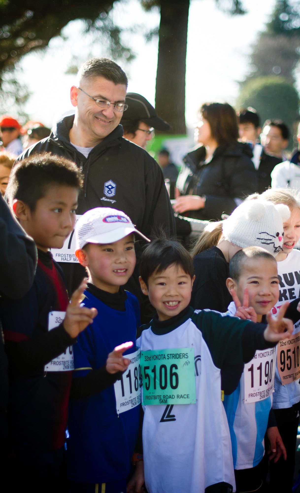 YOKOTA AIR BASE, Japan -- Chief Master Sgt. Manuel Roblesreynoso, 374th Airlift Wing command chief, stands behind a group of Japanese children posing for pictures before the 5K race at the annual Frostbite Run Jan. 13, 2013, at Yokota Air Base, Japan. Team Yokota hosts this event every year to reinforce the positive relationship between the Japanese and U.S. service members. (U.S. Air Force photo by Staff Sgt. Stacy Moless)