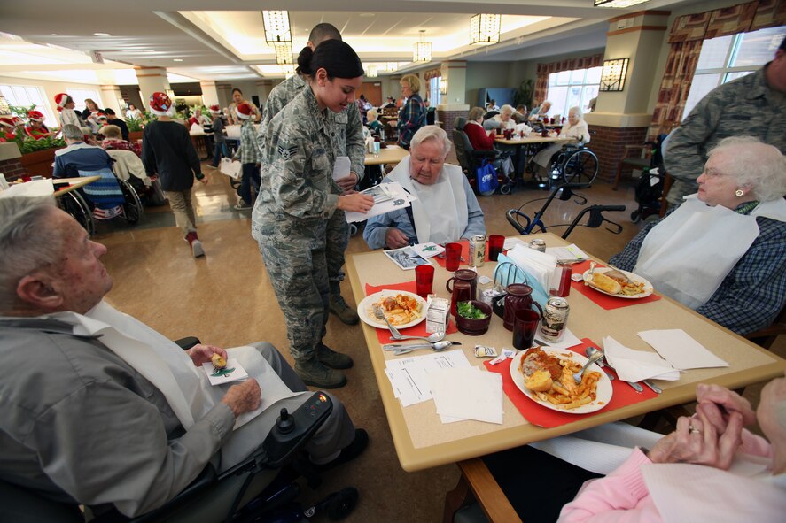 A Vineland Veterans Memorial Home resident is given a card by Senior Airman Aimee Figueroa, 108th Wing, who was among Airmen from the 108th Wing, stationed at Joint Base McGuire-Dix-Lakehurst, N.J., and the 177th Fighter Wing at Egg Harbor Township, N.J., both with the New Jersey Air National Guard, who were joined by fourth graders from the Seaview School in Linwood, N.J. for the Annual Holiday "Songfest" at the Vineland Veterans Memorial Home, Vineland N.J., Dec. 13, 2012. (Air National Guard photo by Master Sgt. Mark C. Olsen)