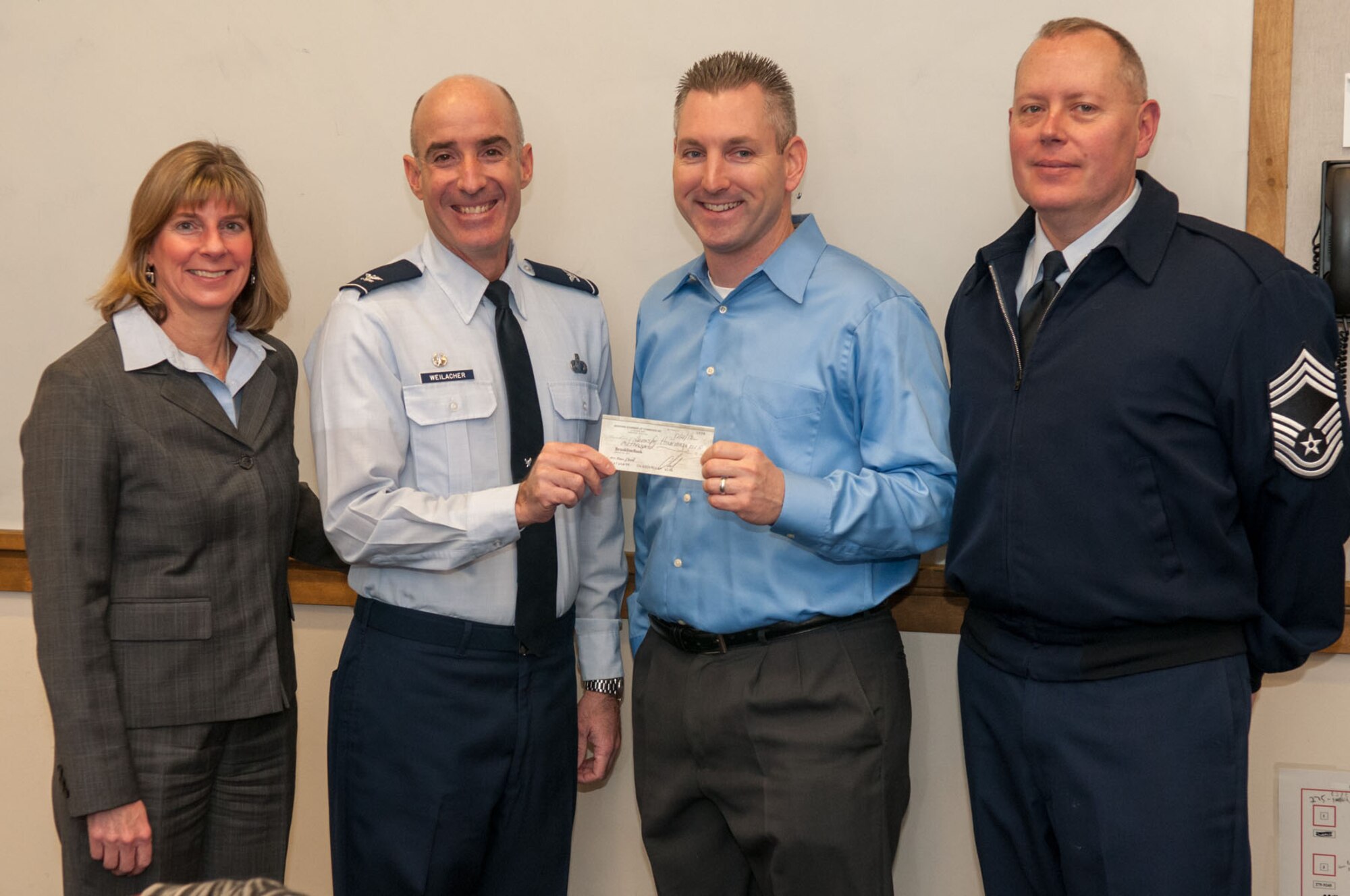BEDFORD, Mass. – Josh Cohen (second from right), Bedford Chamber of Commerce president, and Pam Brown (left), Bedford Chamber of Commerce chairman, present a check to Col. Lester A. Weilacher, 66th Air Base Group commander, and Chief Master Sgt. David Huerd, 66th Air Base Group superintendent, during a meeting at the Bedford Police Department Jan. 10. The money will be used to support the next Heroes Homecoming. (U.S. Air Force photo by Rick Berry)