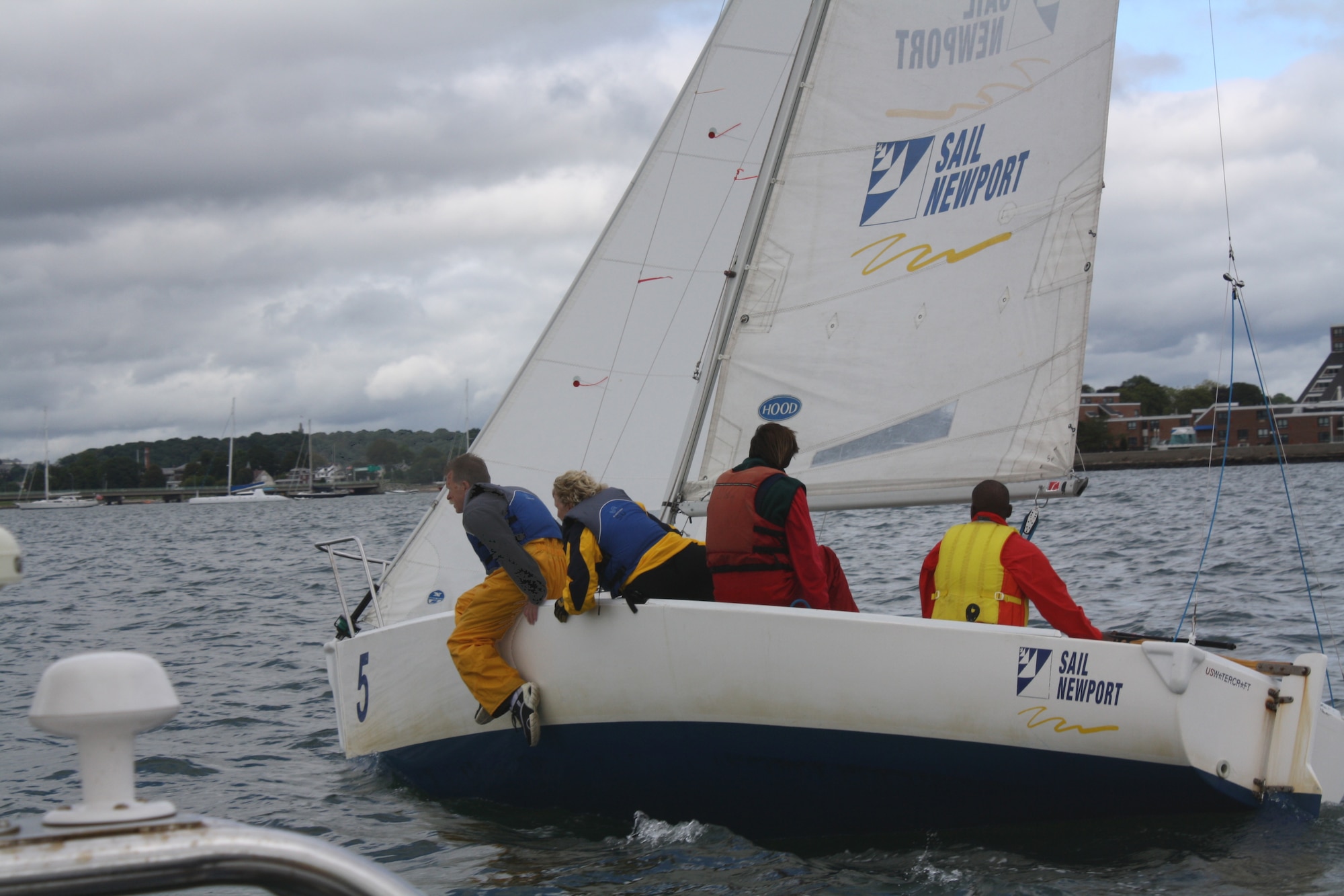 HANSCOM AIR FORCE BASE, Mass.—Hanscom employee Harry Berman (far left) uses his weight to allow the boat to sail its fastest during the final leg of the last race at the National Blind Sailing Championship in Newport, R.I., last summer. Berman is a sighted guide at SailBlind, the first organized sailing program in the United States specifically created to provide instructional and competitive sailing to blind and visually impaired persons. (Courtesy photo)