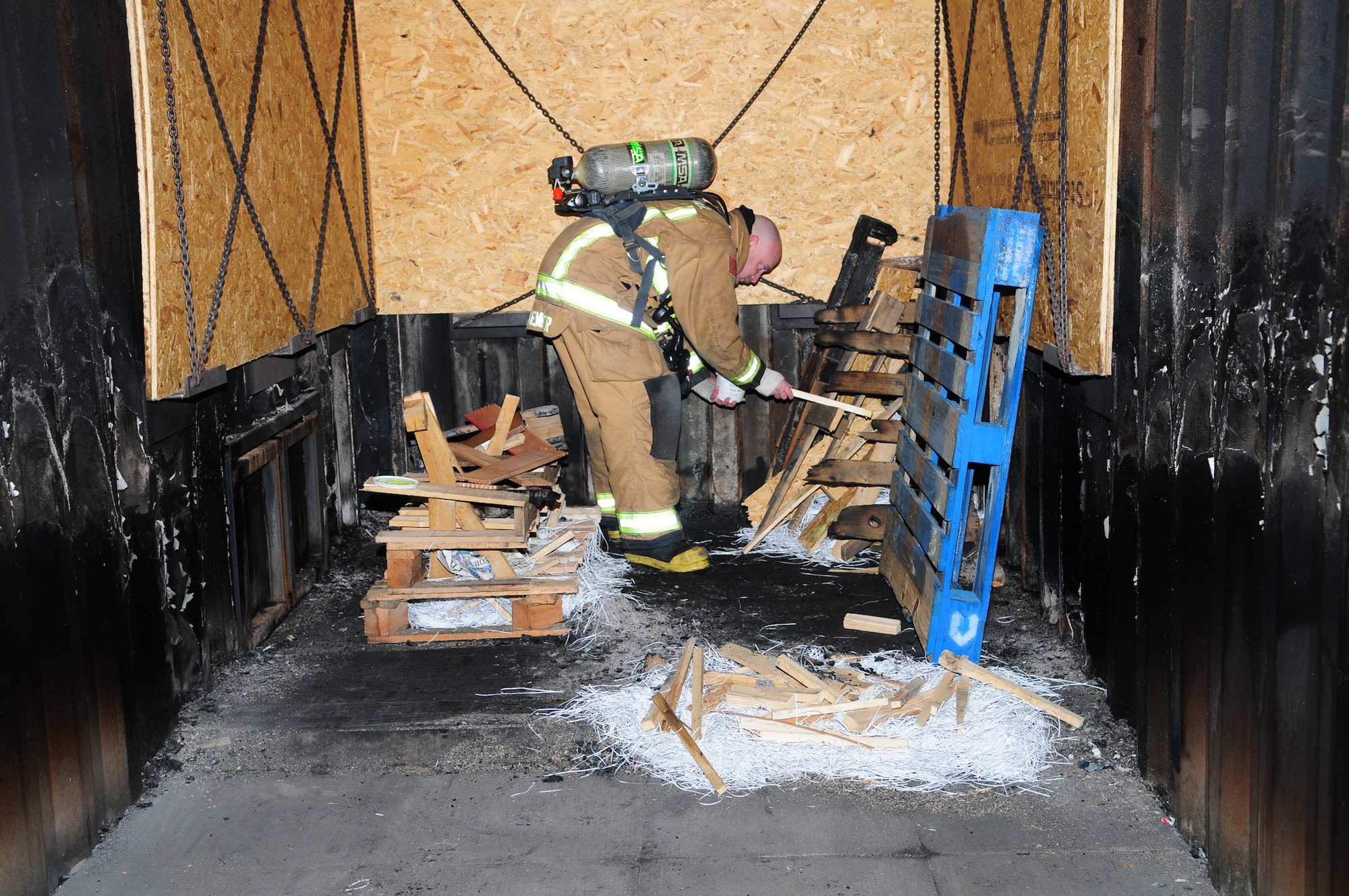 Master Sgt. Matthew Luetkemeyer, 100th Civil Engineer Squadron Fire Department assistant chief of fire training, from Warrenton, Mo., applies an accelerant to a wood stack to ignite a fire in the compartment fire behavior trainer Jan. 10, 2013, at RAF Mildenhall, England. Going through the fire trainer significantly increases the RAF Mildenhall’s firefighters’ knowledge and experience of fighting a compartment fire. (U.S. Air Force photo by Karen Abeyasekere/Released)