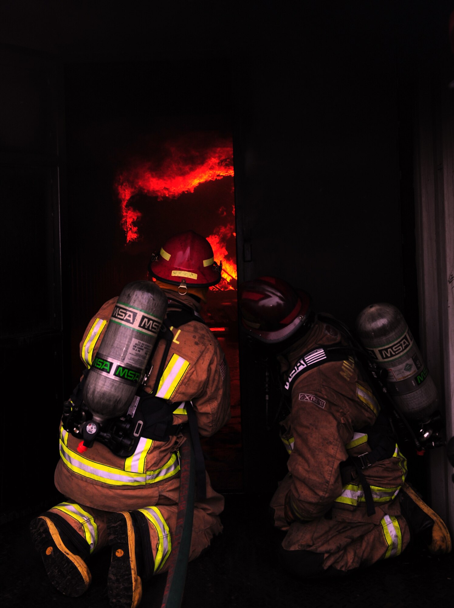 From left, firefighters from the 100th Civil Engineer Squadron Fire Department, Tech. Sgt. Joseph Mrus, from Warren, Ohio, and Watch Manager David Bootman, from Feltwell, Norfolk, discuss the safest way to deal with a fire Jan. 10, 2013, in the compartment fire behavior trainer at RAF Mildenhall, England, before entering the trainer to extinguish the blaze. (U.S. Air Force photo by Karen Abeyasekere/Released)