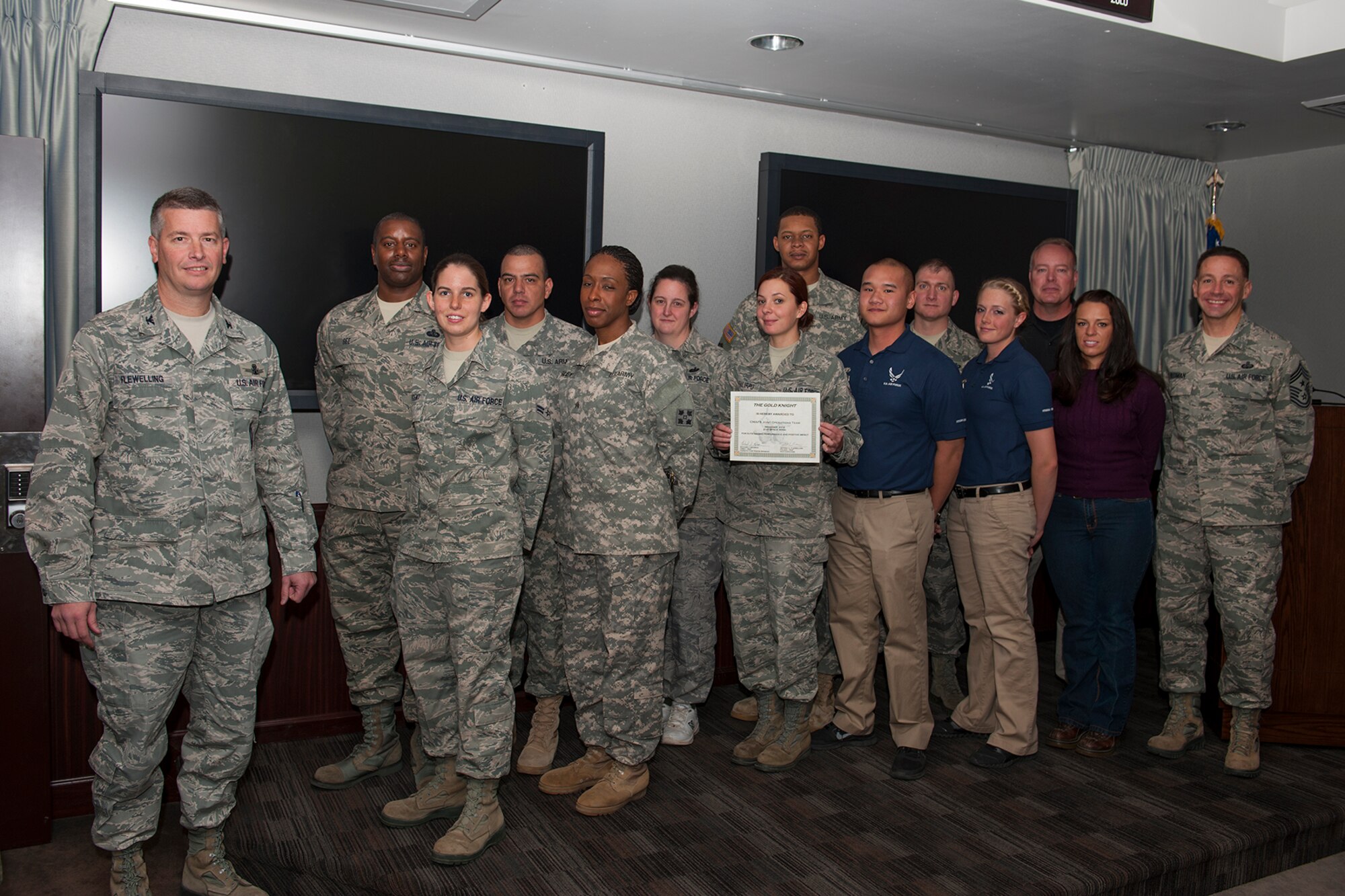 Col. Jeffrey Flewelling (left), 21st Space Wing vice commander, and Chief Master Sgt. Richard Redman (right), 21st SW command chief, present the Gold Knight award to a joint team who provided exercise support to a button-up exercise at Cheyenne Mountain Air Force Station. (U.S. Air Force photo)