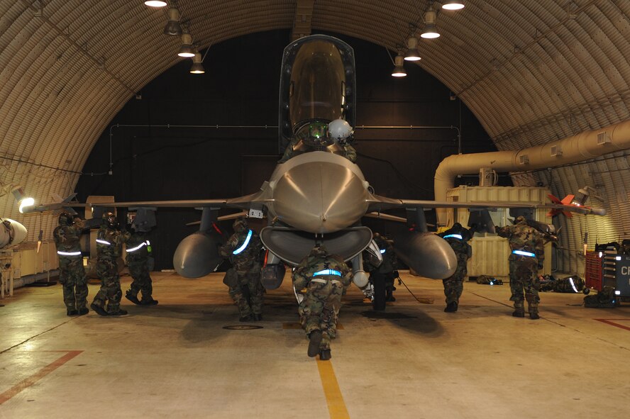 Members of the 35th Aircraft Maintenance Unit guide an F-16 Fighting Falcon into a hangar during exercise Beverly Midnight 13-1 at Kunsan Air Base, Republic of Korea, Jan. 17, 2013. The aircraft needed to be decontaminated following a simulated attack and 35th AMU members were being assessed on the ability to accomplish the goal quickly and effectively. (U.S. Air Force photo by Staff Sgt. Jonathan Fowler/Released)