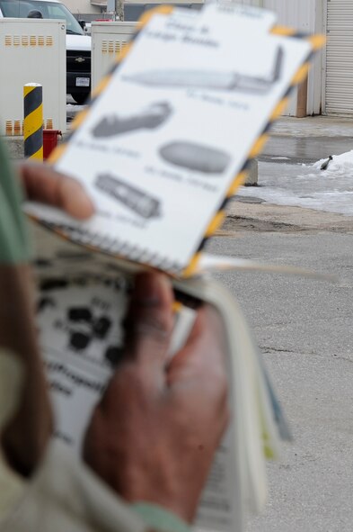A Wolf Pack member uses his Airman’s Manuel to determine the type of unexploded ordnance is in front of him during exercise Beverly Midnight 13-1 at Kunsan Air Base, Republic of Korea, Jan. 17, 2013. The ordinance was found during a post-attack reconnaissance sweep after the simulated tactical ballistic missile attack. (U.S. Air Force photo by Senior Airman Marcus Morris/Released)