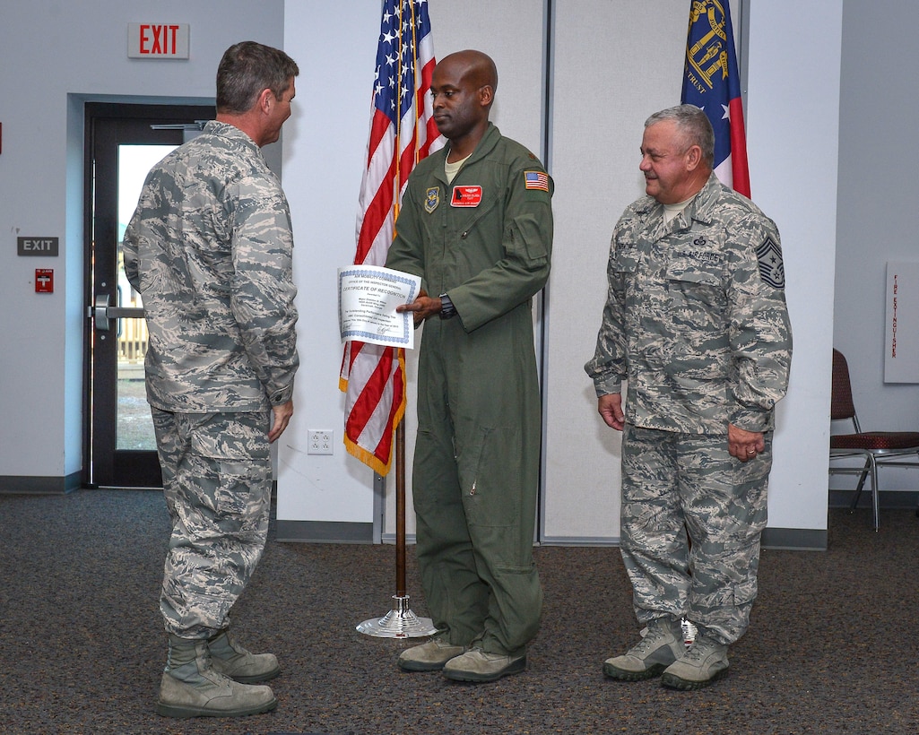 National Guard Maj. Sheldon Wilson receives a certificate of Outstanding Performance from the 165th Airlift Wing Commander Col. Keith Edenfield, January 16, 2013 at Savannah Air National Guard Base in Garden City, Ga. Wilson is the Wing Plans officer and OPSEC Program Manager for the wing and was recognized by the Inspector General as an outstanding performer. Command Chief Master Sgt. Hewshal Thornton also attended the presentation. (National Guard photo by Tech. Sgt. Charles Delano/released)