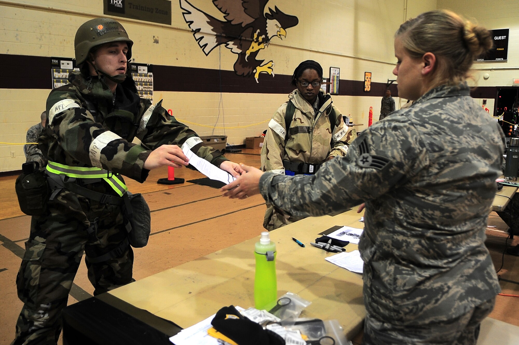 U.S. Air Force Senior Airman Bryson Hendrix, 4th Operations Support Squadron airfield management apprentice, hands a checklist to Senior Airman Brandi Kleb, 4th Security Forces Squadron personnel support, while transitioning into the exercise play area on Seymour Johnson Air Force Base, N.C., Jan. 17, 2013. The list includes required items during an Operational Readiness Exercise. (U.S. Air Force photo/Airman 1st Class Aubrey White/Released)