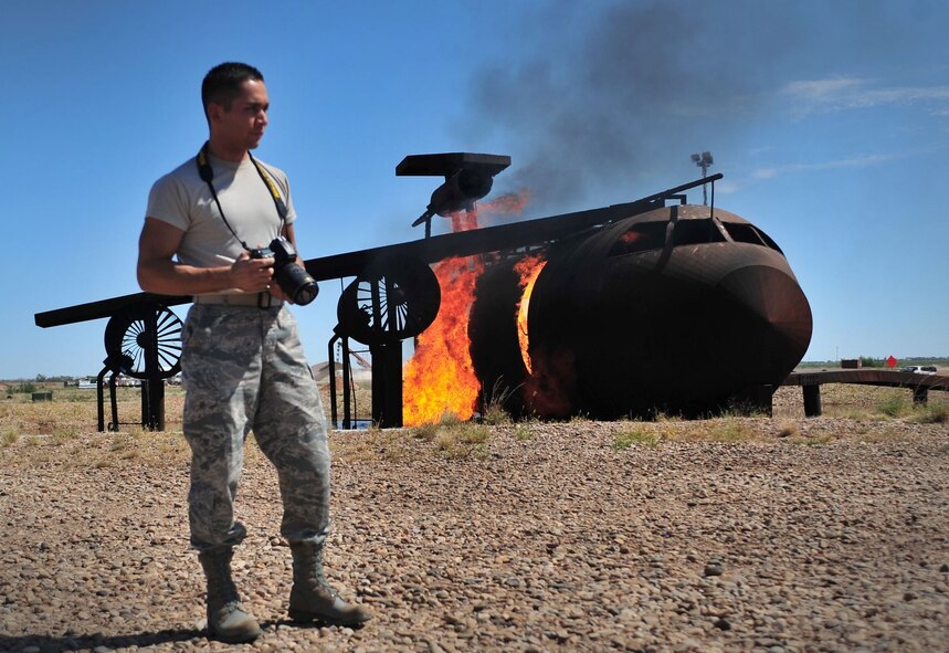 U.S. Air Force Senior Airman Alexxis Pons Abascal, 27th Special Operations Wing Public Affairs specialist, prepares to photograph firefighter joint-training at the burn pit at Cannon Air Force Base, N.M., Aug. 2, 2012. Public Affairs members at Cannon play an integral part in shaping and maintaining the public’s image of not just their installation, but the Air Force as a whole. (U.S. Air Force photo/Airman 1st Class Eboni Reece) 