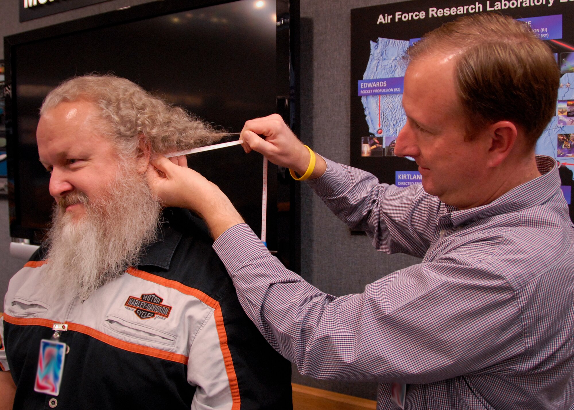 Brian Mitchell, the Air Force Research Laboratory marketing representative, measures Kurt Burgess, the AFRL security manager for munitions structure, for hair and beard growth at Eglin Air Force Base, Fla., Dec. 21.  Burgess raised money by accepting a challenge to not cut his hair or shave for a year.  He raised $5,000 for the effort and donated the money to the Wounded Warrior project.  When Burgess started, he was clean shaven and bald.  Upon completion, his hair measured six and a half inches and his and beard measured seven inches.  (U.S. Air Force photo/Kevin Gaddie)    