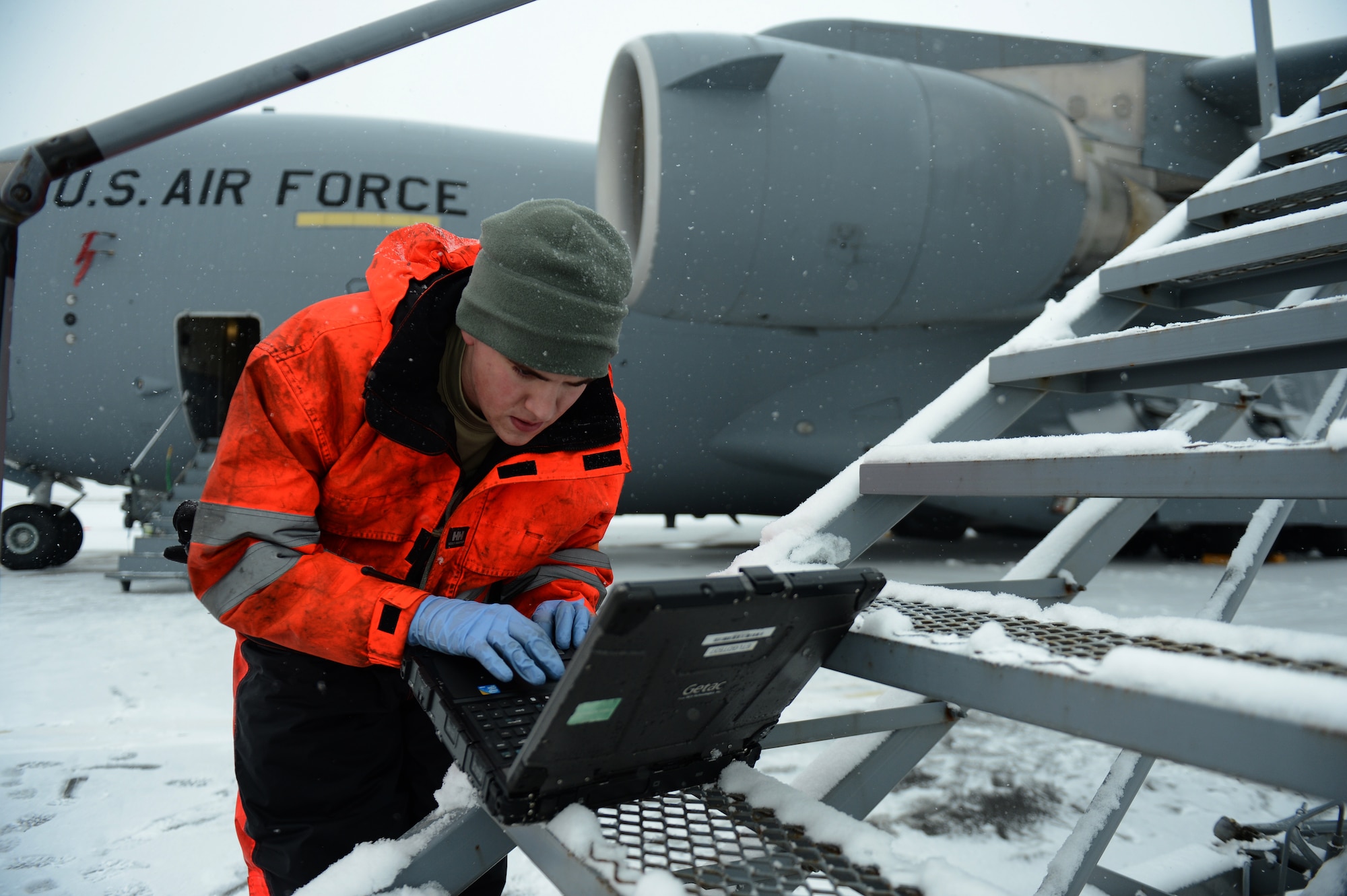 SPANGDAHLEM AIR BASE, Germany – U.S. Air Force Senior Airman Craig Fox, 726th Air Mobility Squadron hydraulics technician from Glen Burnie, Md., reads a technical order on his laptop prior to working on a C-17 Globemaster III cargo aircraft Jan. 15, 2013. Maintainers from the 726th prepared the aircraft for a winter storm that hit the base recently. (U.S. Air Force photo by Airman 1st Class Gustavo Castillo/Released)