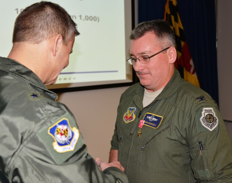General Scott Kelly, 175th Wing commander presents the Bronze Star Medal to Colonel Kevin J. Campbell, 175th Operations Group commander on January 13th. Campbell distinguished himself by meritorious achievement as Deputy Commander and Commander, 455th Expeditionary Operations Group, 455th Air Expeditionary Wing while engaged in ground operations against the enemy at Bagram Airfield, Afghanistan from April 28, 2012 to September 2012. During this period Campbell commanded the theater’s largest combat air group, consisting of over 900 joint forces operating 74 aircraft in nine squadrons and one detachment in support of Operation Enduring Freedom. He developed robust residual base defense operation synchronizing intelligence inputs from five agencies and aircraft from nine Air Force and Army units with the ground scheme of maneuver within the Bagram security zone. His efforts succeeded in reducing the number of attacks against the base and aircraft to the lowest level in over four years. (National Guard photo by Senior Master Sgt. Ed Bard)