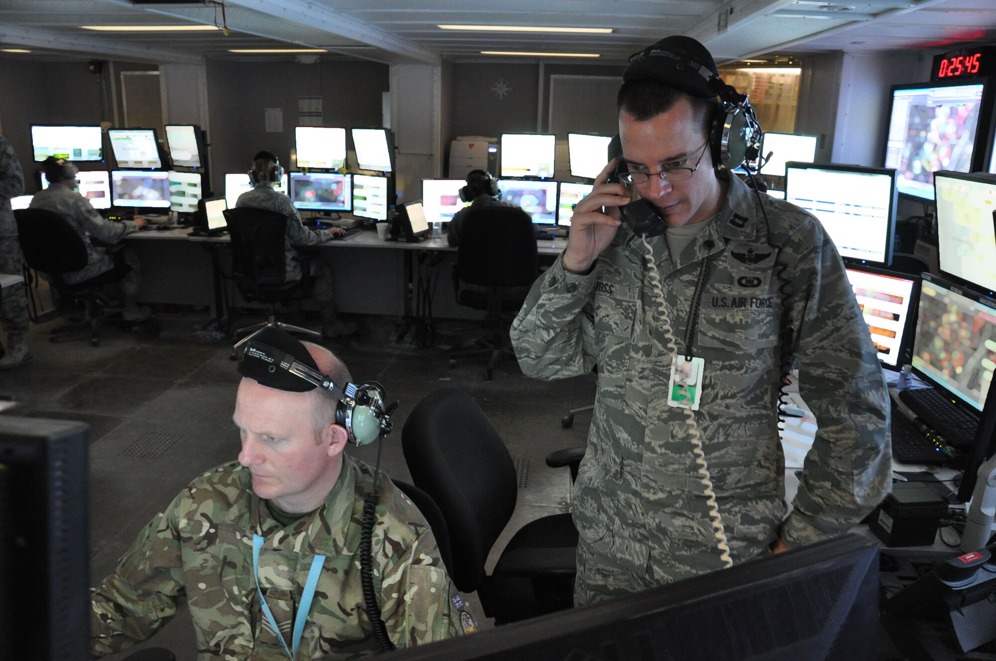 British Air Force Staff Sgt. Daz Finney, air surveillance officer, and Capt. James Ross, mission group battle suite commander, coordinate taskings, Jan. 9. The 71st Expeditionary Air Control Squadron monitors airspace throughout the coalition area of responsibility in Southwest Asia and serve as a failsafe measure for other forward air monitoring services. The outgoing rotation is the final group of air surveillance professionals from Aviano Air Base, Italy, and will return home soon. (U.S. Air Force photo/Master Sgt. Christian Michael)
