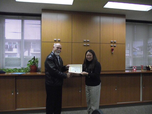 Gary Bernhard, Marine All-Weather Fighter Attack Squadron 242 family readiness officer, presents Miyuki Gray, Japanese Lifestyle Insights, Networking, Knowledge, and Skills trainer, a certificate of appreciation for her volunteer work at the Marine Corps Family Team Building, Dec. 17, 2012. Gray received the award helping supply an American spouse with a Japanese translator to find a daycare in town. Gray volunteers her time away from work to ensure that Japanese spouses are comfortable adapting to a military lifestyle as well as an American one.