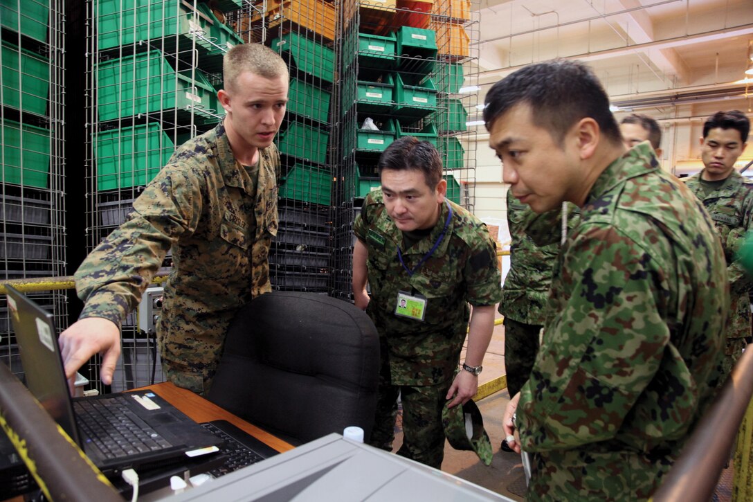 Lance Cpl. Gregory A. Crisler discusses distribution tracking systems with Japan Ground Self-Defense Force officers during a tour of Combat Logistics Regiment 35’s facilities Jan. 8 at Camp Kinser. During the tour, JGSDF officers visited and discussed operations with CLR-35 Marines, with a focus on amphibious logistics operations. “We are always excited to participate in these exchanges,” said JGSDF Col. Yoshiki Adachi, chief of logistics operations and plans with the JGSDF’s Logistics Management Division. “Working today with CLR-35 provided us with an experience we can learn from and use in the future.” Crisler is a warehouse clerk with Combat Logistics Battalion 3, CLR-35, 3rd Marine Logistics Group, III Marine Expeditionary Force. (Photo by Lance Cpl. Anne K. Henry)


