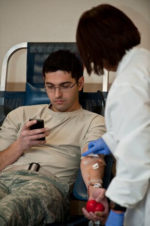 U.S. Air Force Airman 1st Class Fardad Alimehri, 820th RED HORSE Squadron civil engineer, turns his attention to his smartphone while giving blood during a blood drive at Outdoor Recreation Center Jan. 18, 2013, Nellis Air Force Base, Nev. The 57th Wing and United Blood Services hosted the blood drive which was open to all Nellis members, civilians, and their families. (U.S. Air Force photo by Senior Airman Daniel Hughes)