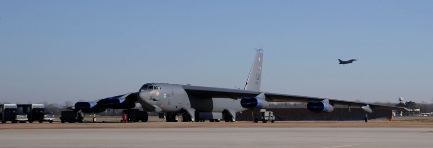 A B-52H Stratofortress awaits maintenance on the flightline as an F-16 Fighting Falcon flies past at Barksdale Air Force Base, La., Jan. 18. For the past 60 years the B-52 has been a mainstay of the Air Force?s bomber force by providing the capability to strike from anywhere in the world and deliver precision munitions to the battlefield. (U.S. Air Force photo/Airman 1st Class Andrew Moua)