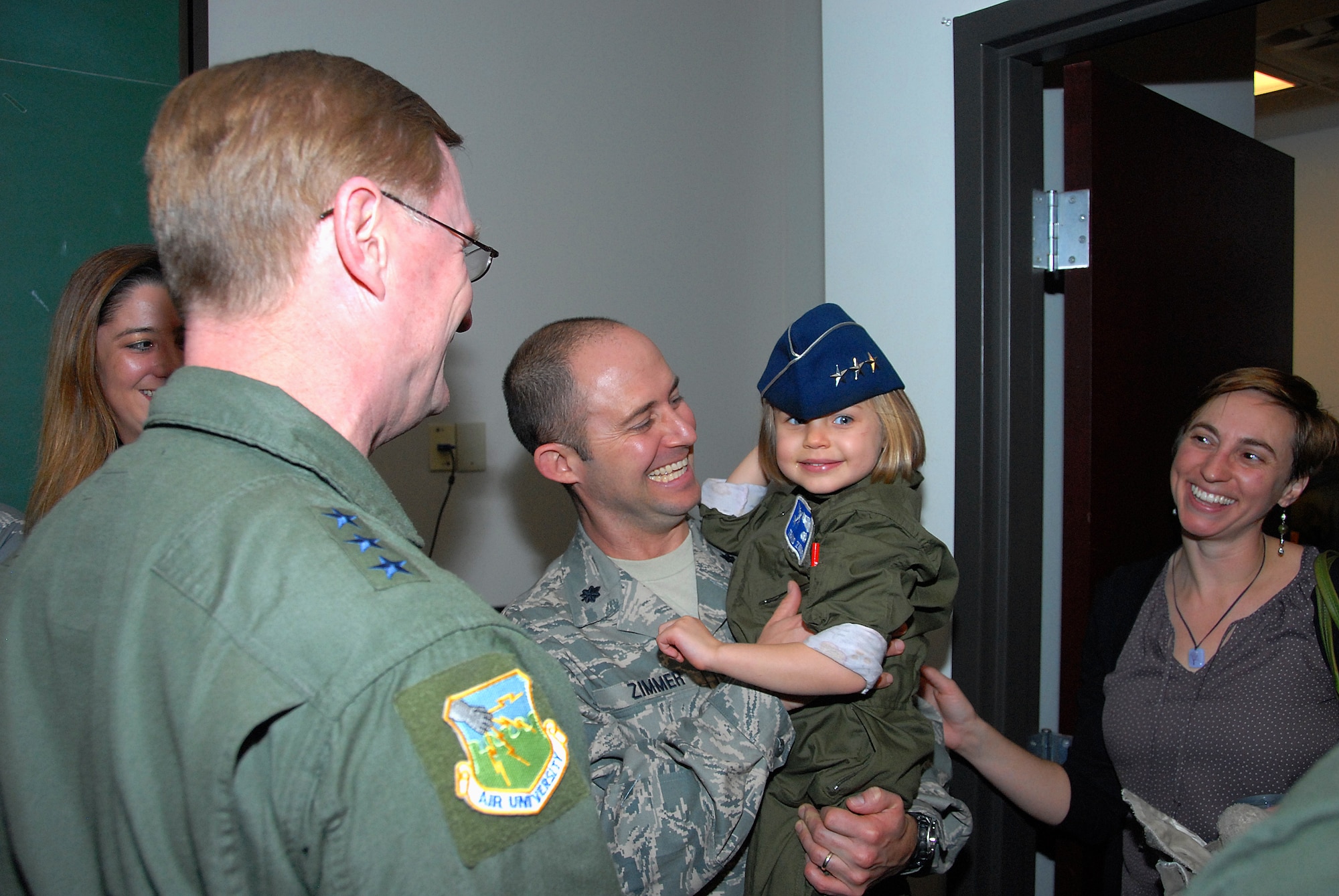 Lt. Col. Travis Zimmer of the 908th Airlift Wing, along with wife, Amy, react as Lt. Gen. David Fadok, commander and president of Air University shares his three-star cover with the Zimmer's daughter, Florence, prior to the deployment of Airmen from the 908th Jan. 10. (U.S. Air Force photo by Gene H. Hughes)