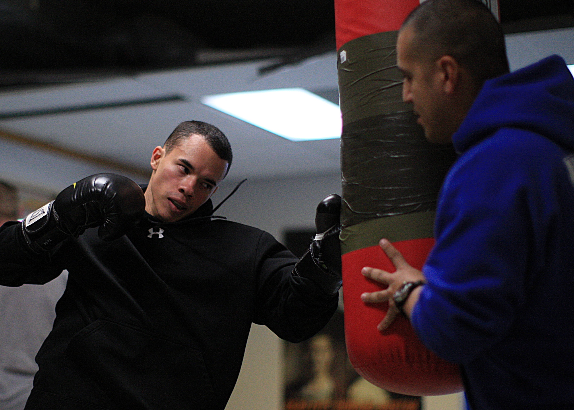 Senior Airman Richard Purrier, 90th Security Forces Group Tactical Response Force, swings at a heavy bag held by his coach, Tech. Sgt. Bobby De Leon, 90th SFG TRF team lead, during training Jan. 10 on F. E. Warren Air Force Base, Wyo. Purrier trains daily to prepare for his upcoming competition for selection to the All Air Force Boxing Team Jan. 21 at Lackland Air Force Base, Texas. (U.S. Air Force photo by Matt Bilden)