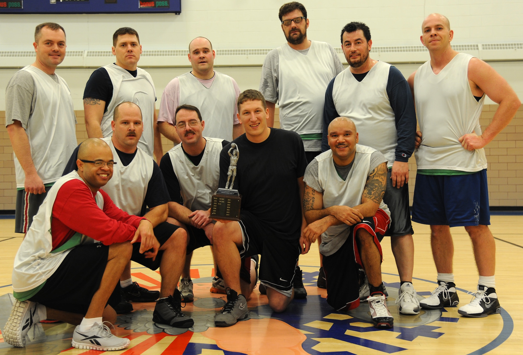 The 69th Reconnaissance Group over-30 basketball team celebrate their championship victory Jan. 9, 2013, at the Fitness Center on Grand Forks Air Force Base, N.D. The 69th RG team defeated the 319th Security Forces Squadron 46-40 to take the trophy. (U.S. Air Force photo/Airman 1st Class Xavier Navarro)