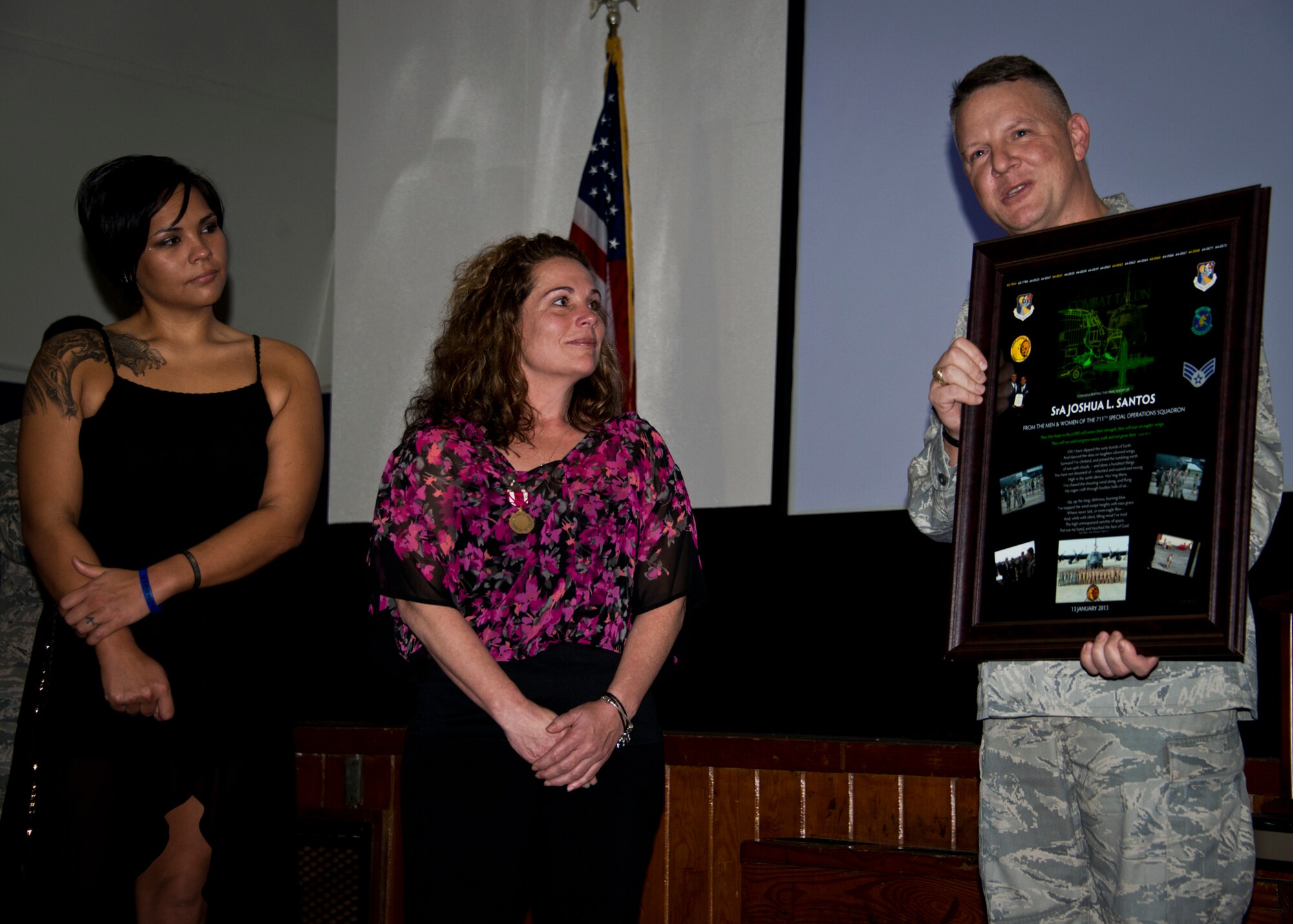 Lt. Col. Christopher Stegner, from the 919th Operations Group, presents a memento to Lisa Santos and Alyssa Degeyter, the mother and sister of Senior Airman Josh Santos, during his memorial Jan. 13 at Duke Field, Fla.  Santos passed away Nov. 26 from colon cancer.  He was a radio operator with the 711th SOS.  During the memorial, it was announced the Duke Field gym would be renamed Santos Strength in his honor.   (U.S. Air Force photo/Tech. Sgt. Samuel King Jr.)