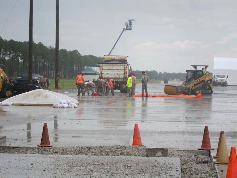 After the U.S. Army Engineer Research and Development Center Airfield Damage Repair (ADR) team train the airmen, members of the Rapid Engineer Deployable, Heavy Operational Repair Squadron Engineer (RED HORSE) squadron use the materials, equipment and methods to repair craters during a simulated wet weather demonstration at Tyndall Air Force Base, Fla. The protective covers are placed the work underway to prevent dilution of the repair materials and over the repaired area to enable rapid set to take place.