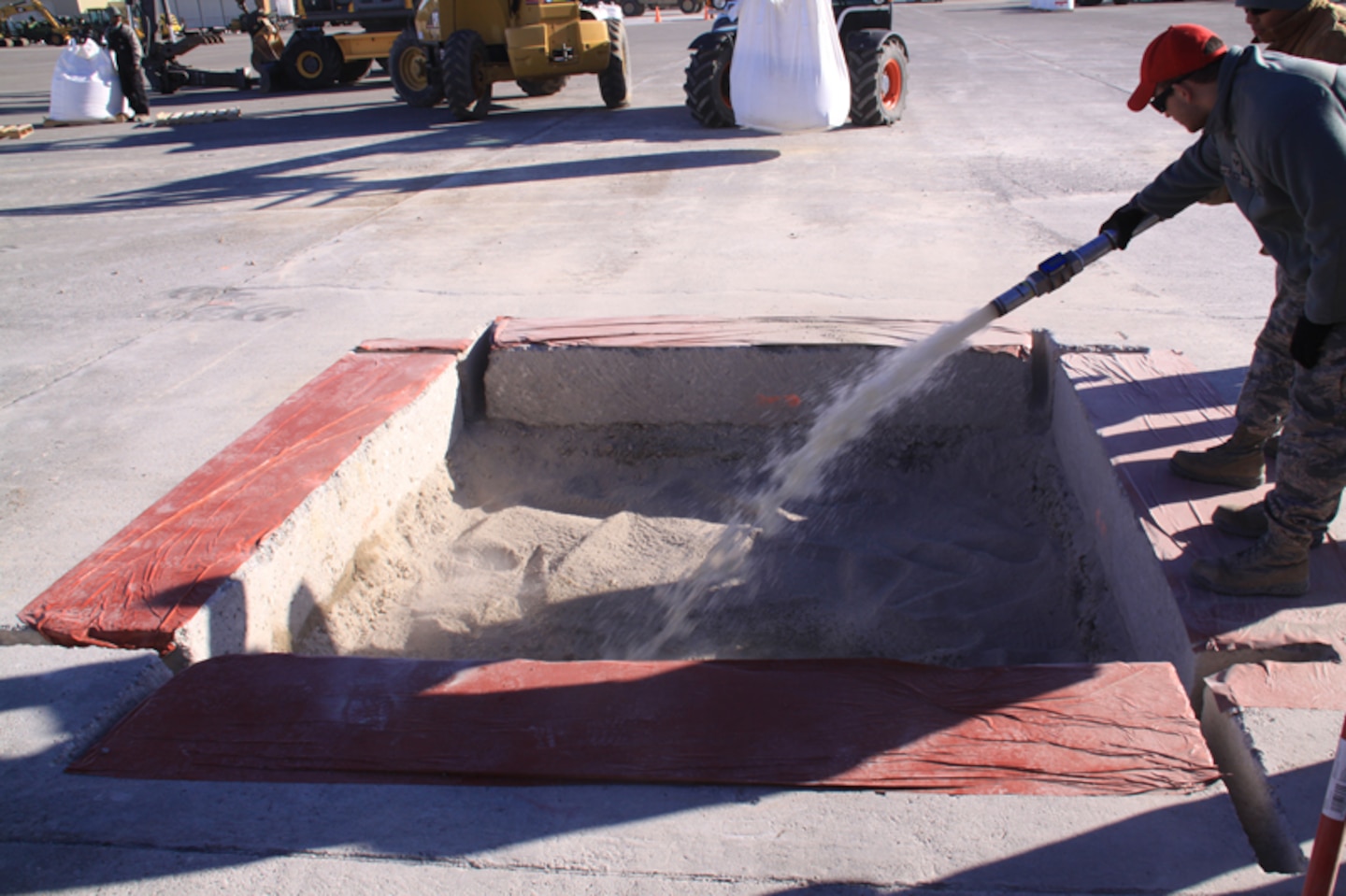 RED HORSE team member places fill materials in crater.