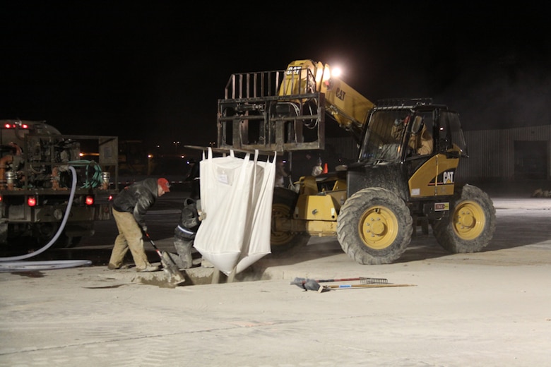 RED HORSE team members place fill material in crater.