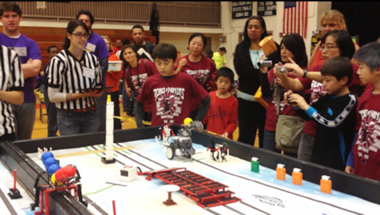 Robo-Ninja team members, coaches, and families look on as their robot performs during the winning table run.
