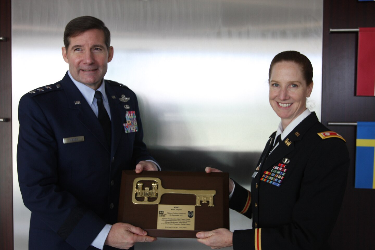 Lt. Col. Michelle Garcia, U.S. Army Corps of Engineers Europe District deputy commander, presents a commemorative key plaque to Lt. Gen. Frank Kisner, NATO Special Operations Headquarters commander, following the unit’s headquarters facility ribbon-cutting at SHAPE in Mons, Belgium Dec. 12, 2012. NATO special operations forces, comprised of 26 member nations and 3 non-NATO partners, completed a new, state-of-the-art 23,000-square-foot administrative headquarters building. The USACE-managed $19 million project was completed in 23 months through a partnership with the joint venture contractors Bilfinger-Berger and Besix. During construction, 116 local subcontractors and suppliers were involved and local building materials were utilized. The facility meets strict environmental and energy savings standards and is U.S. Green Buildings Council LEED Silver certifiable. 