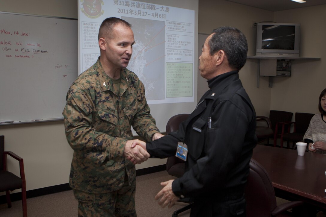 Colonel John E. Merna, commanding officer of the 31st Marine Expeditionary Unit, greets Hironubu Sugawara, a city assembly member from Oshima Island, during a visit here, Jan. 14. The Oshima Island residents were invited to the 31st MEU headquarters for a brief on the unit’s capabilities and the Marines’ response to the earthquake and tsunami disaster in 2011, known as Operation Tomodachi. The guests, who were directly affected by the disaster, were on Okinawa to escort 20 children for the Oshima Island Homestay Program, a program created by Marine Corps Installations Pacific, now in its second year. The 31st MEU is the Marine Corps’ force in readiness for the Asia-Pacific region and the only continuously forward deployed MEU. 