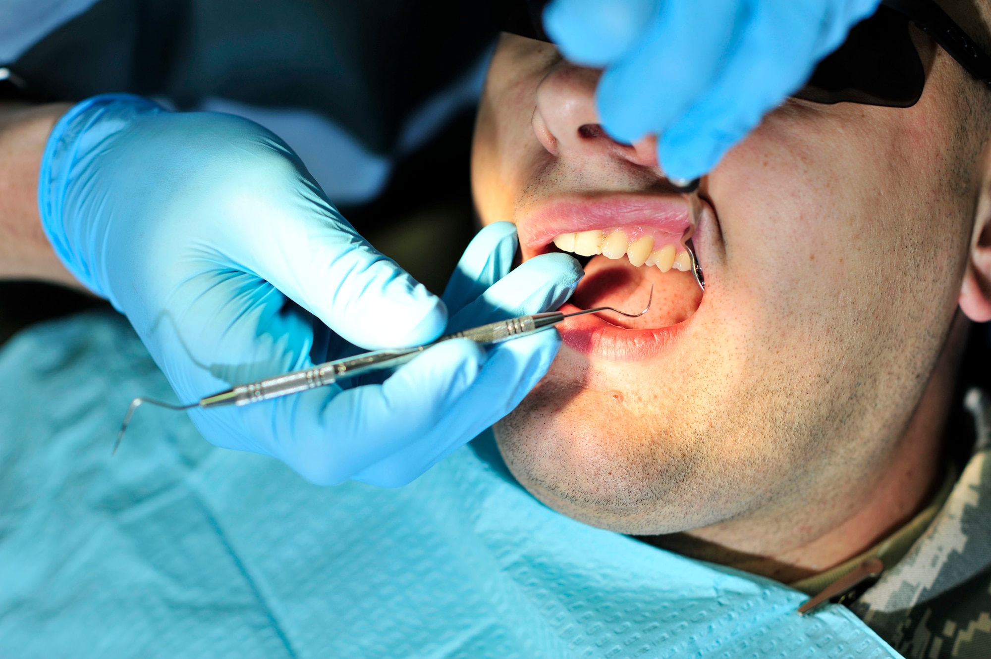 SOUTHWEST ASIA -- U.S. Air Force Maj. Tad Tholstrom, 380th Air Expeditionary Medical Group chief of dental services, performs a routine exam for Senior Airman Dino Beharic, 380th EMDG unit deployment manager. Tholstrom, deployed from Travis Air Force Base, Calif., is able to perform most mainstream dental treatments such as composite resins and temporary crowns.   (U.S. Air Force photo/Tech. Sgt. Christina M. Styer)