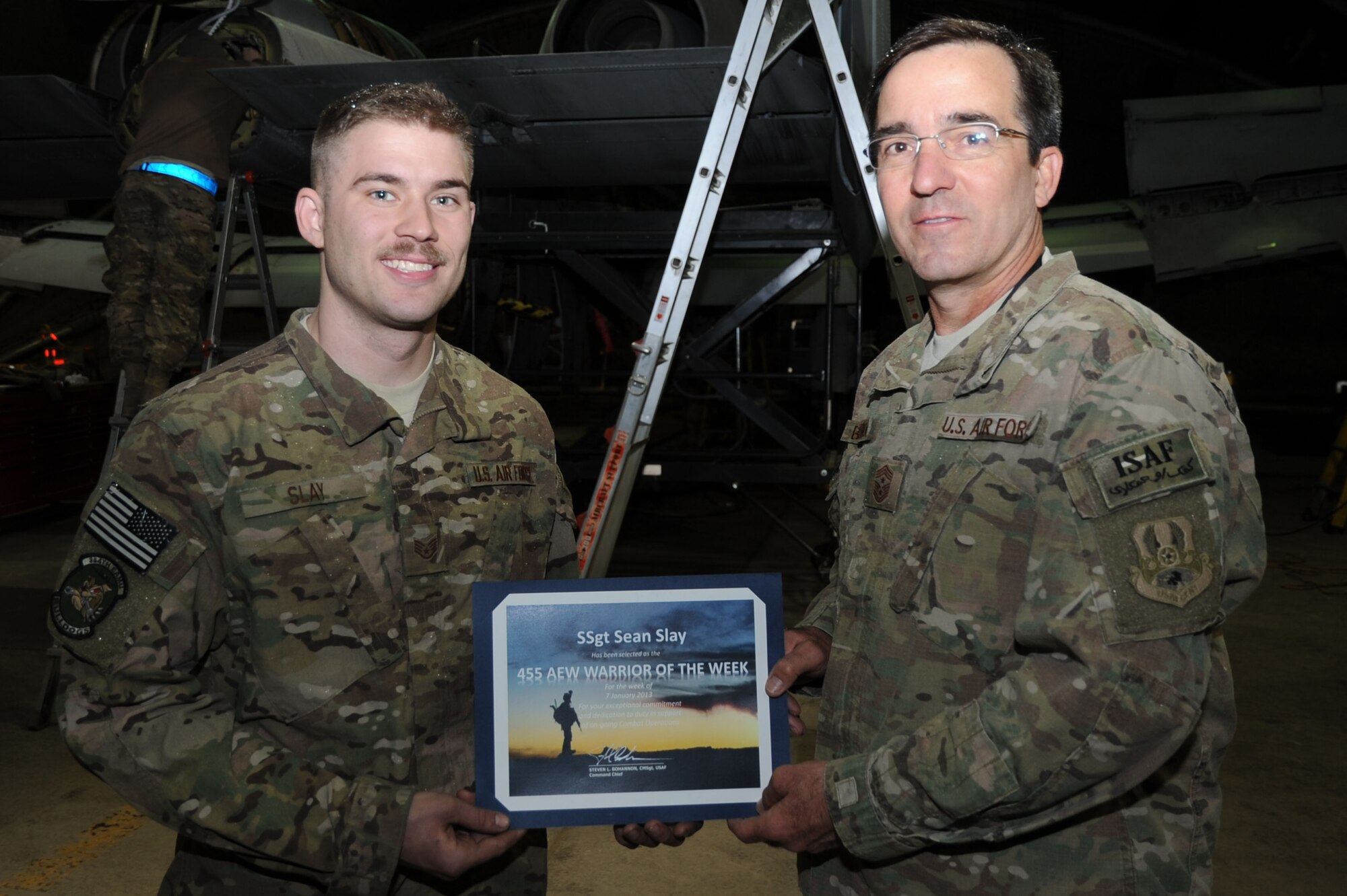 Chief Master Sgt. Steve Bohannon, Command Chief Master Sergeant of the 455th Air Expeditionary Wing, presents the 'Warrior of the Week' award to Staff Sgt. Sean Slay, 455th Expeditionary Aircraft Maintenance Squadron avionics systems craftsman, on Bagram Airfield, Afghanistan, Jan. 16, 2013. Slay manages maintenance of targeting pods for the A-10 Thunderbolt II aircraft. (U.S. Air Force photo/Staff Sgt. David Dobrydney)