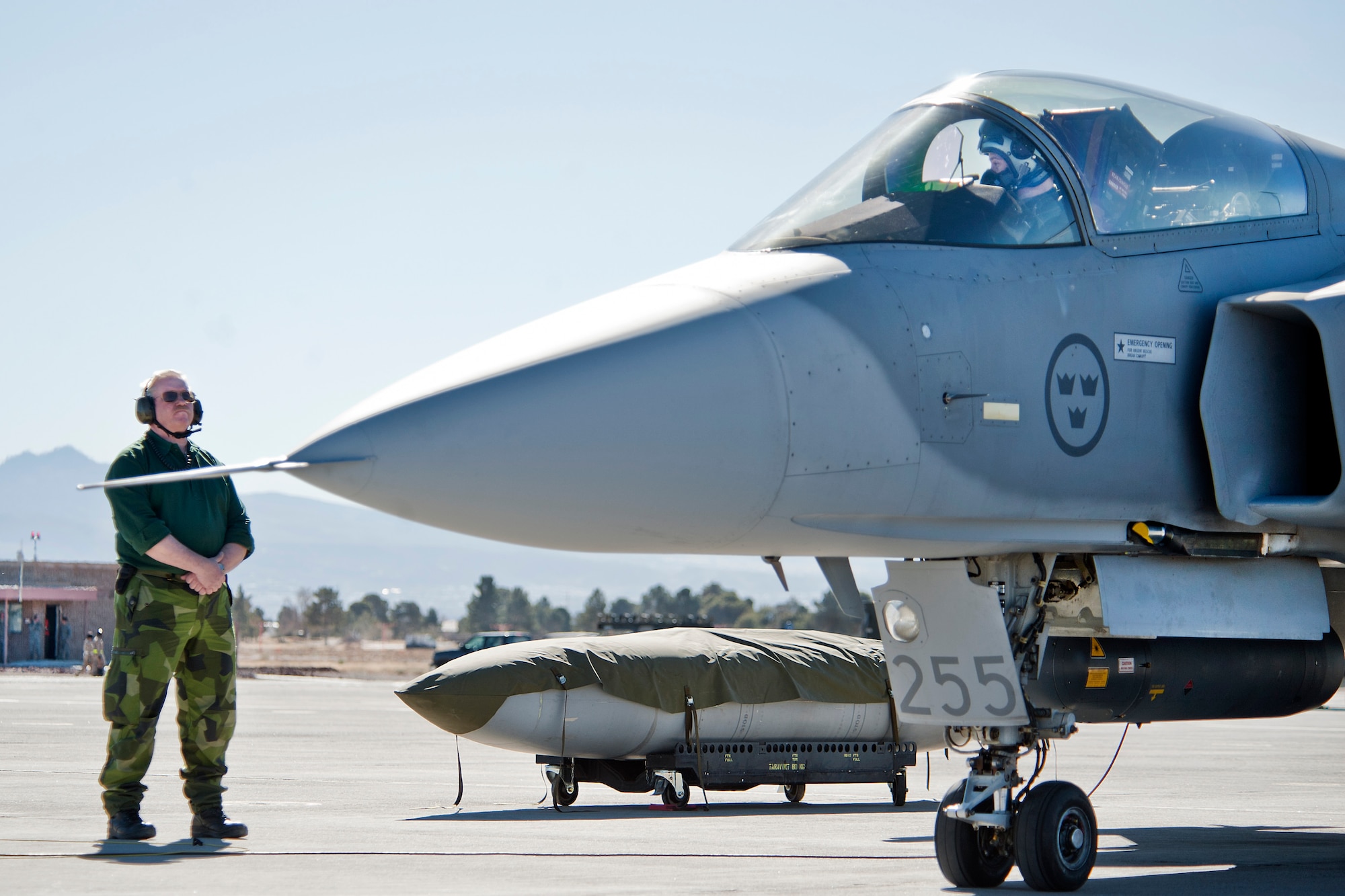 A Swedish Air Force crew chief from the 172nd Fighter Squadron marshals a JAS-39C Gripen on the Nellis Air Force Base flight line Jan. 21, 2013. The Swedish AF's JAS-39C Gripen will participate in Red Flag 13-2 from Jan. 21 through Feb. 1, 2013. (U.S. Air Force photo by Lawrence Crespo)
