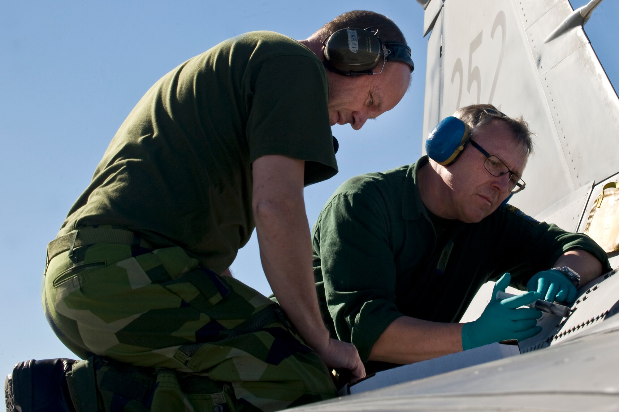 Swedish technicians from the 172nd Fighter Reconnaissance Squadron, attach a panel to a JAS-39 Gripen during RED FLAG 13-2, Jan. 21, 2013, at Nellis Air Force Base, Nev. The JAS-39 Gripen is a lightweight single-engine multirole fighter manufactured by the Swedish aerospace company Saab. (U.S. Air Force photo by Senior Airman Matthew Lancaster)
