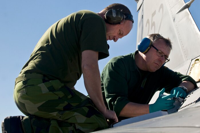 Swedish technicians from the 172nd Fighter Reconnaissance Squadron, attach a panel to a JAS-39 Gripen during RED FLAG 13-2, Jan. 21, 2013, at Nellis Air Force Base, Nev. The JAS-39 Gripen is a lightweight single-engine multirole fighter manufactured by the Swedish aerospace company Saab. (U.S. Air Force photo by Senior Airman Matthew Lancaster)