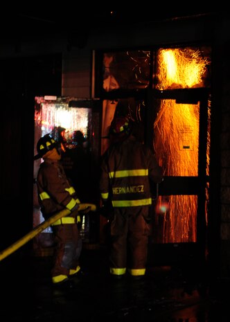 Beale Air Force Base firefighters are illuminated by a fire burning inside the 9th Civil Engineer Squadron's main building Jan. 21, 2013. The fire started at approximately 2:30 p.m., and firefighters from Beale and the surrounding community fought the fire throughout the night. (U.S. Air Force photo by Senior Airman Shawn Nickel/Released)