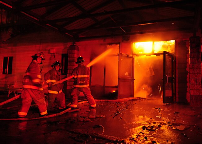 Beale Air Force Base firefighters are illuminated by a fire burning inside the 9th Civil Engineer Squadron's main building Jan. 21, 2013. The fire started at approximately 2:30 p.m. and firefighters from Beale and the surrounding community fought the fire throughout the night. (U.S. Air Force photo by Senior Airman Shawn Nickel/Released)