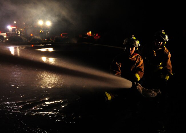 Two firefighters from the 9th Civil Engineer Squadron hose down a hot spot during a structure fire at Beale Air Force Base, Calif., Jan. 21, 2013. The fire started at approximately 2:30 p.m., and firefighters from Beale and the surrounding community fought the fire throughout the night. (U.S. Air Force photo by Senior Airman Shawn Nickel/Released)