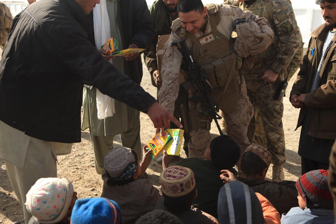 Major Rudy Salcido, officer in charge of Georgian Liaison Team 6, Regimental Combat Team 7, Regional Command Southwest, hands school supplies to a local child in Shir Ghazay, Afghanistan, Jan. 17, 2013.