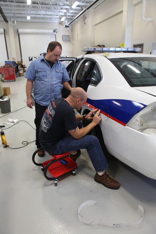 Employees of the Maintenance Support Division aboard Marine Corps Base Camp Lejeune add decals to a new police car Jan. 7. The division is one of many facilities comprising a new complex aboard the base. The complex includes the Marine Air Ground Task Force Information Technology Support Center, known as MITSC, Base Telecommunications, the Cyber Security Division and the Applications Enhancement Division. 