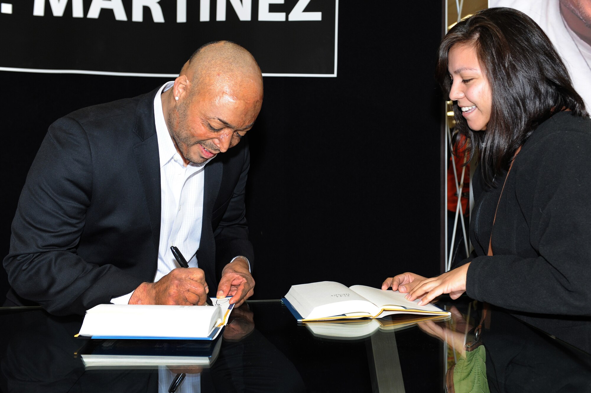 J.R. Martinez, former U.S Army Soldier, celebrity and wounded warrior, signs his book, "Full of Heart" for Kristina Berry at the base exchange Jan. 23, 2013 at Nellis Air Force Base, Nev. Berry thanked Martinez for being an inspiration to her cousin, who received severe burns from an improvised explosion attack, during Operation Iraqi Freedom in 2006. In "Full of Heart", Martinez shares his story in intimate detail; from his upbringing, his time in the Army, his recovery and the indomitable spirit that has made him an inspiration. (U.S. Air Force photo by Staff Sgt. William P. Coleman)
