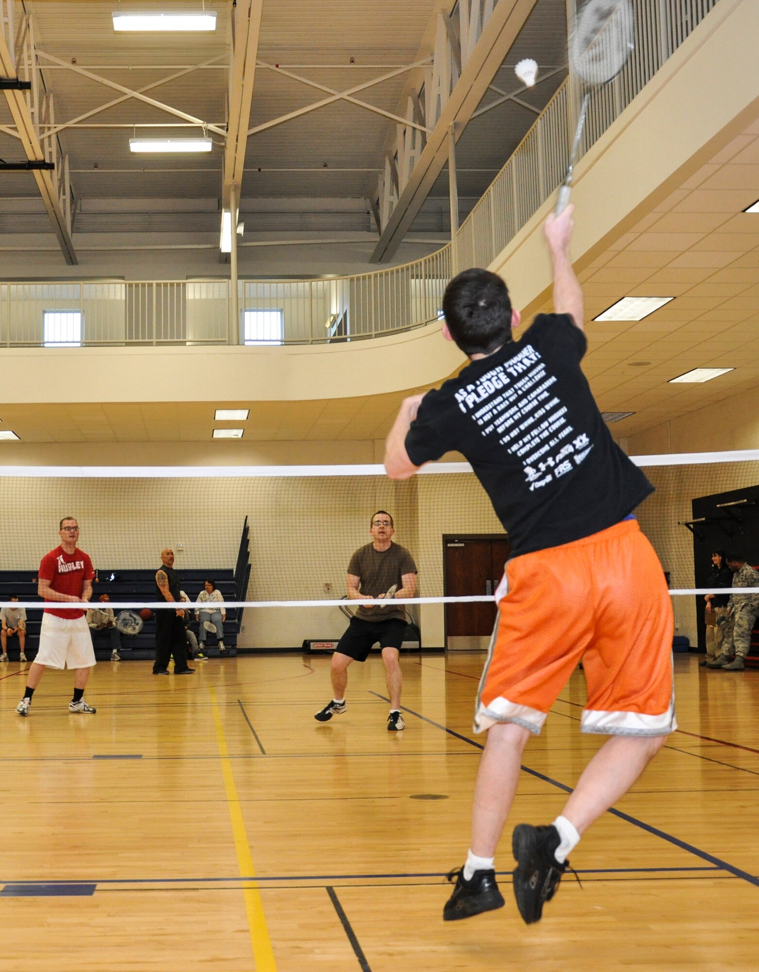 Two opponents look on as Eric Vesey slams the shuttlecock at them during a badminton tournament Jan. 23, 2013, at the Buckley Fitness Center. Vesey and his partner, Alex Sanchez, both from the Air Force Reserve Command’s 310th MSG, attended the tournament to defend last year’s title. (U.S. photo by Staff Sgt. Nicholas Rau/Released)