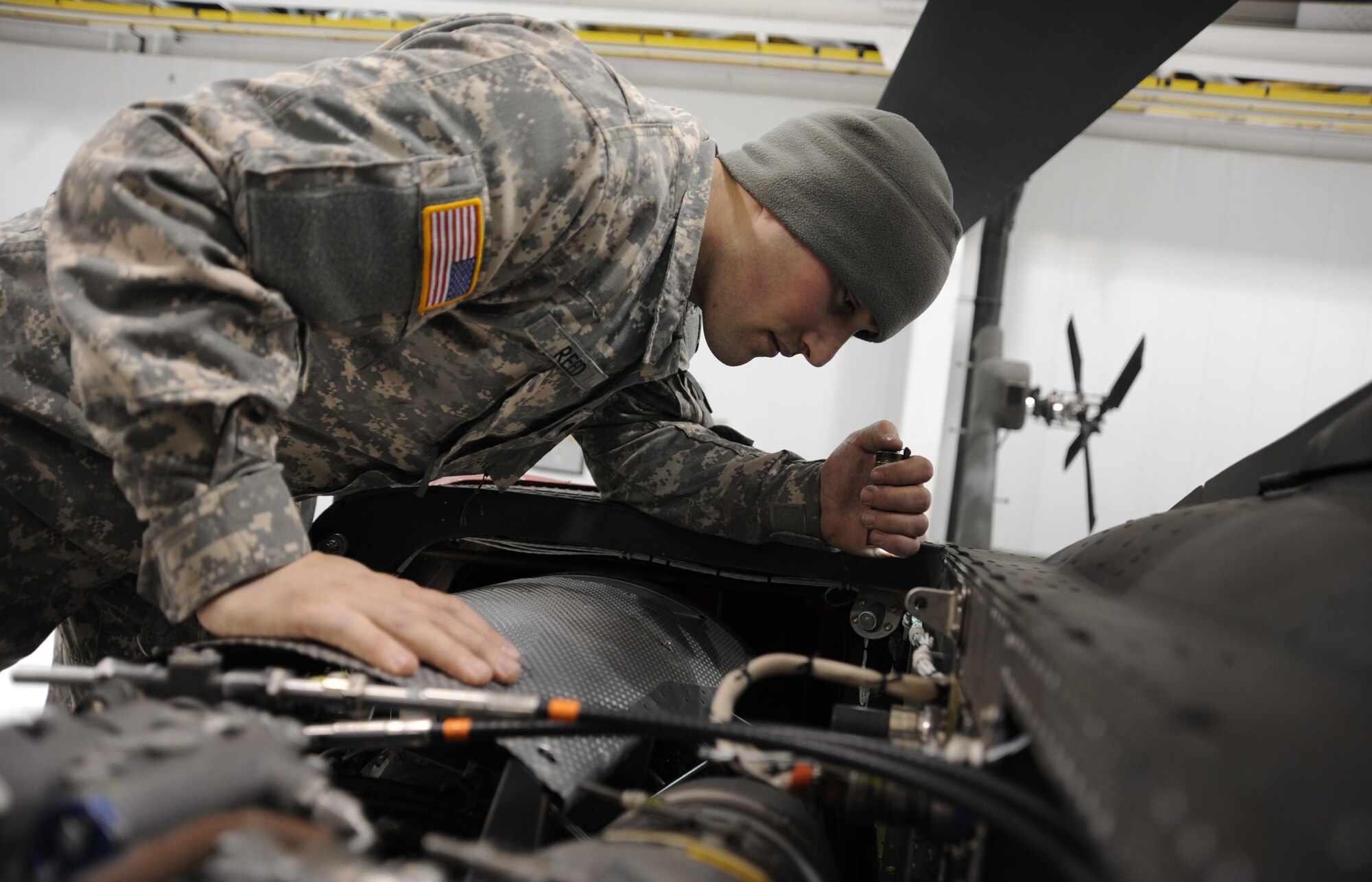 WHITEMAN AIR FORCE BASE, Mo. -- U.S. Army Specialist Jonathan Reed, 1-135th Attack Reconnaissance Battalion AH 64D Apache Longbow crew chief, performs a daily inspection on an AH 64D Apache Longbow, Jan. 16. Daily inspections help Apache mechanics and crew chiefs apply preventative maintenance as a countermeasure against problems that might arise in flight. (U.S. Air Force photo/Staff Sgt. Nick Wilson) (Released)