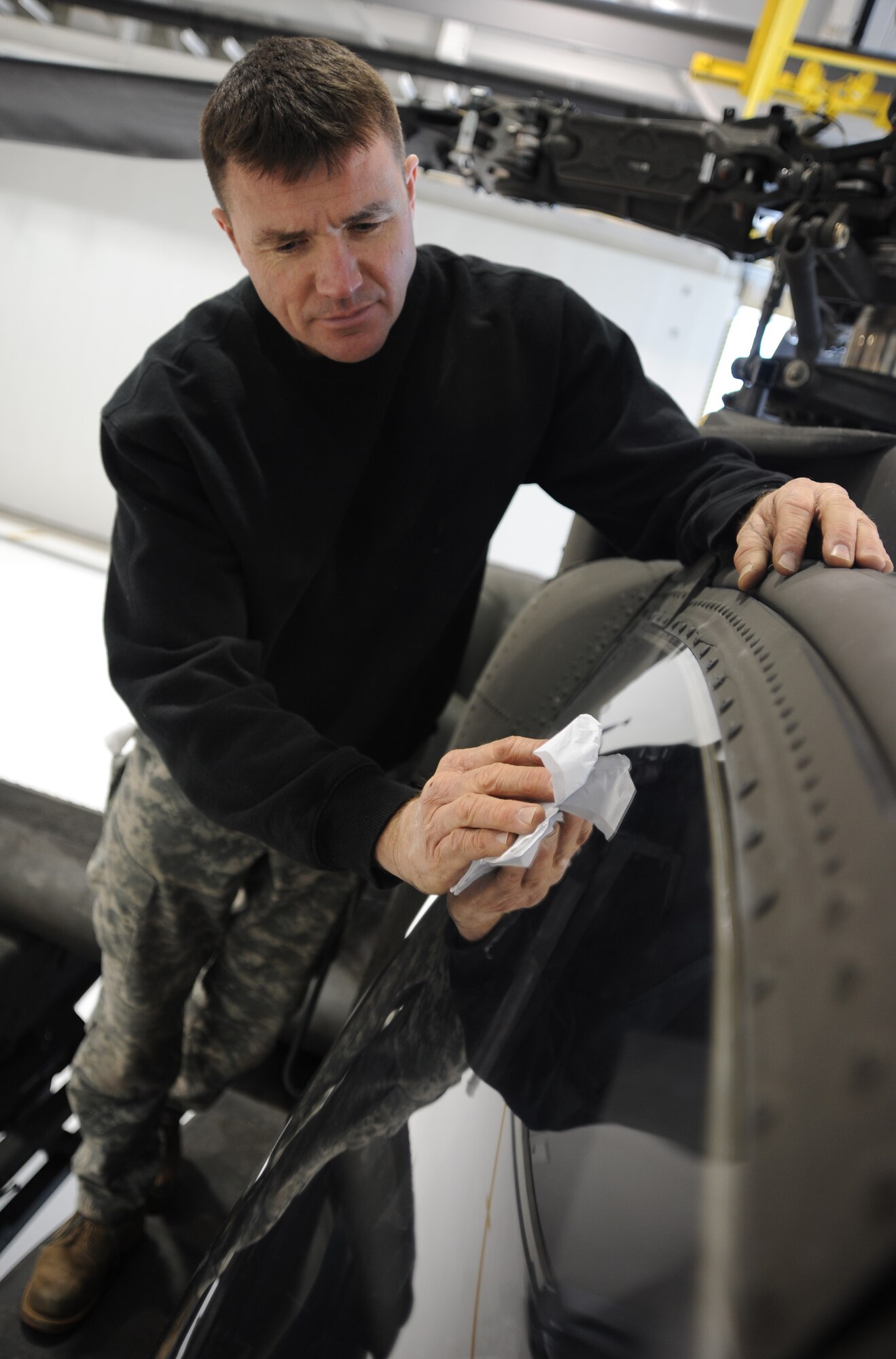 WHITEMAN AIR FORCE BASE, Mo. -- U.S. Army Sgt. Brian Wood, 1-135th Attack Reconnaissance Battalion crew chief, washes the Plexiglass window of an AH 64D Apache Longbow, Jan. 16. The acrylic design on the Apache windows helps keep pilots safe in case an emergency evacuation is necessary. (U.S. Air Force photo/ Staff Sgt. Nick Wilson) (Released)