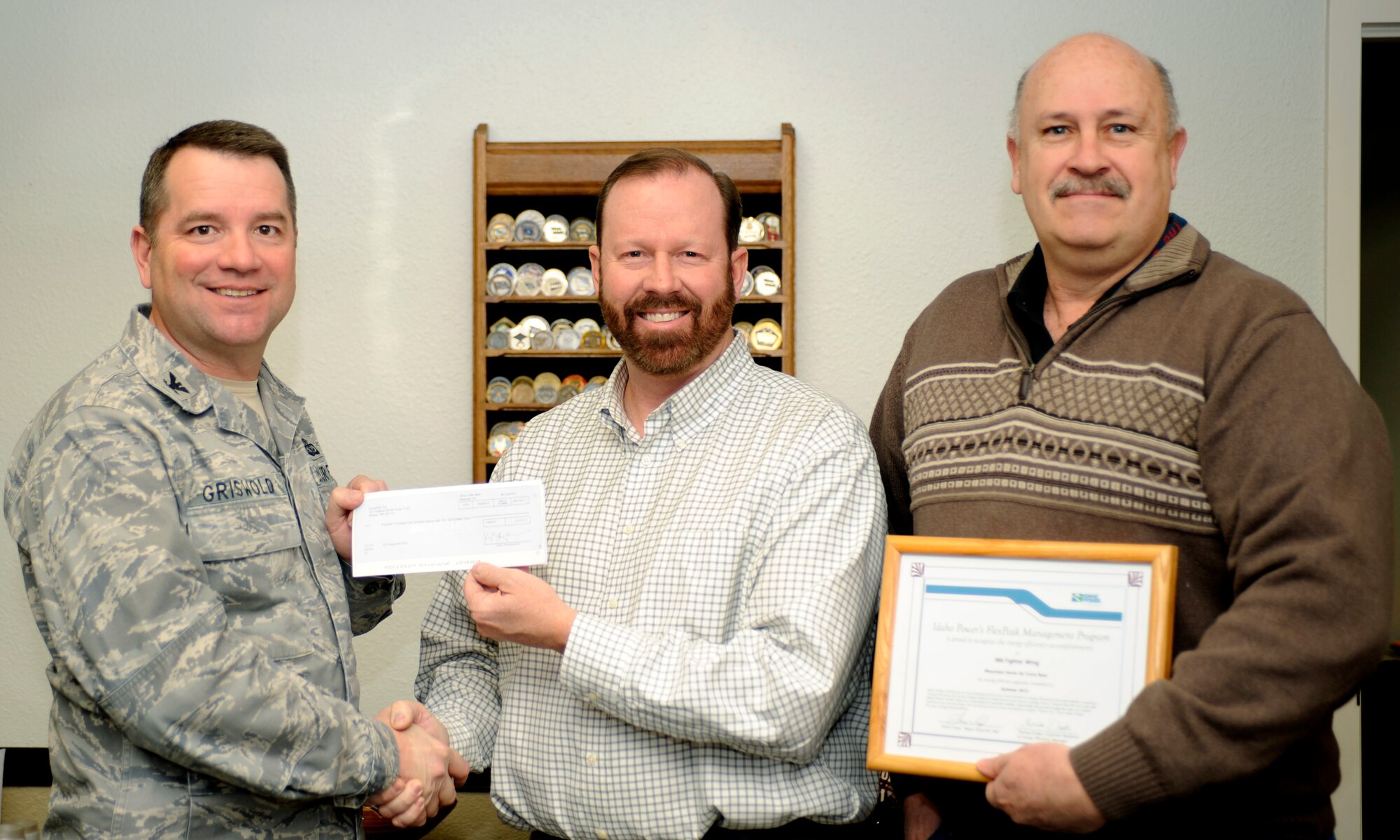 U.S. Air Force Col. Steven Griswold, 366th Mission Support Group commander, receives an incentive check of more than $14,000 from Steve Floyd, major customer representative for Idaho Power, while Base Energy Manage Joseph Armstrong looks on Jan. 16, 2013 on Mountain Home Air Force Base, Idaho. The money was awarded to the base through Idaho Power's Demand Response Program, which rewards businesses for lowering their energy consumption. The funds will go to the 366th Civil Engineer Squadron in support of future energy conservation initiatives.