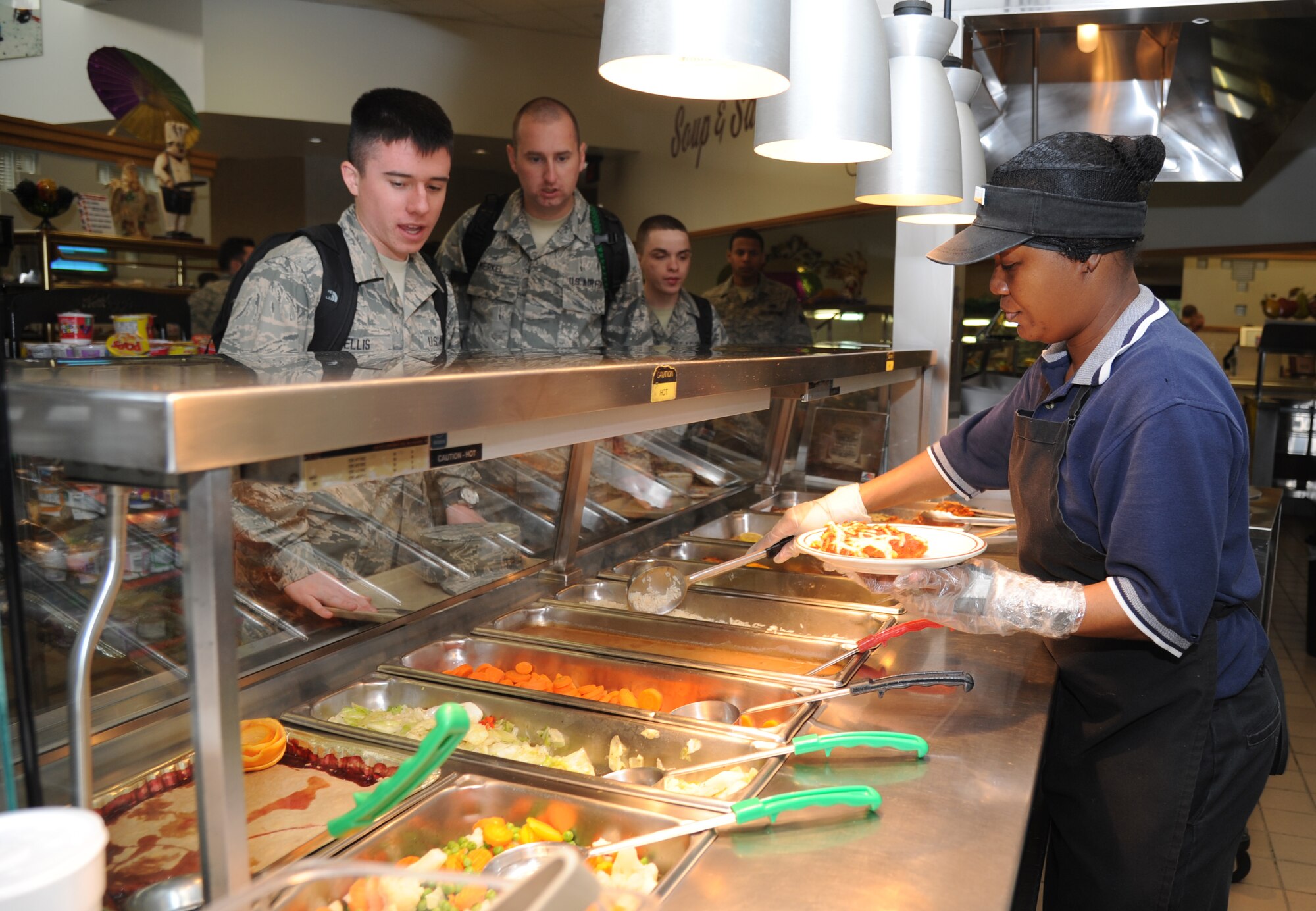 Airman Basic Cody Ellis and Airmen 1st Class Matthew Merkel and Jack Woodman, 334th Training Squadron, are served a meal by Sandra Newsome, line server, at the Azalea Dining Facility Jan. 22, 2013, at Keesler Air Force Base, Miss.  The 81st Force Support Squadron food service operations accommodated a $1.25 million budget cut by shortening hours at the Live Oak Dining facility and expanding hours at Azalea and Magnolia dining halls.  (U.S. Air Force photo by Kemberly Groue)